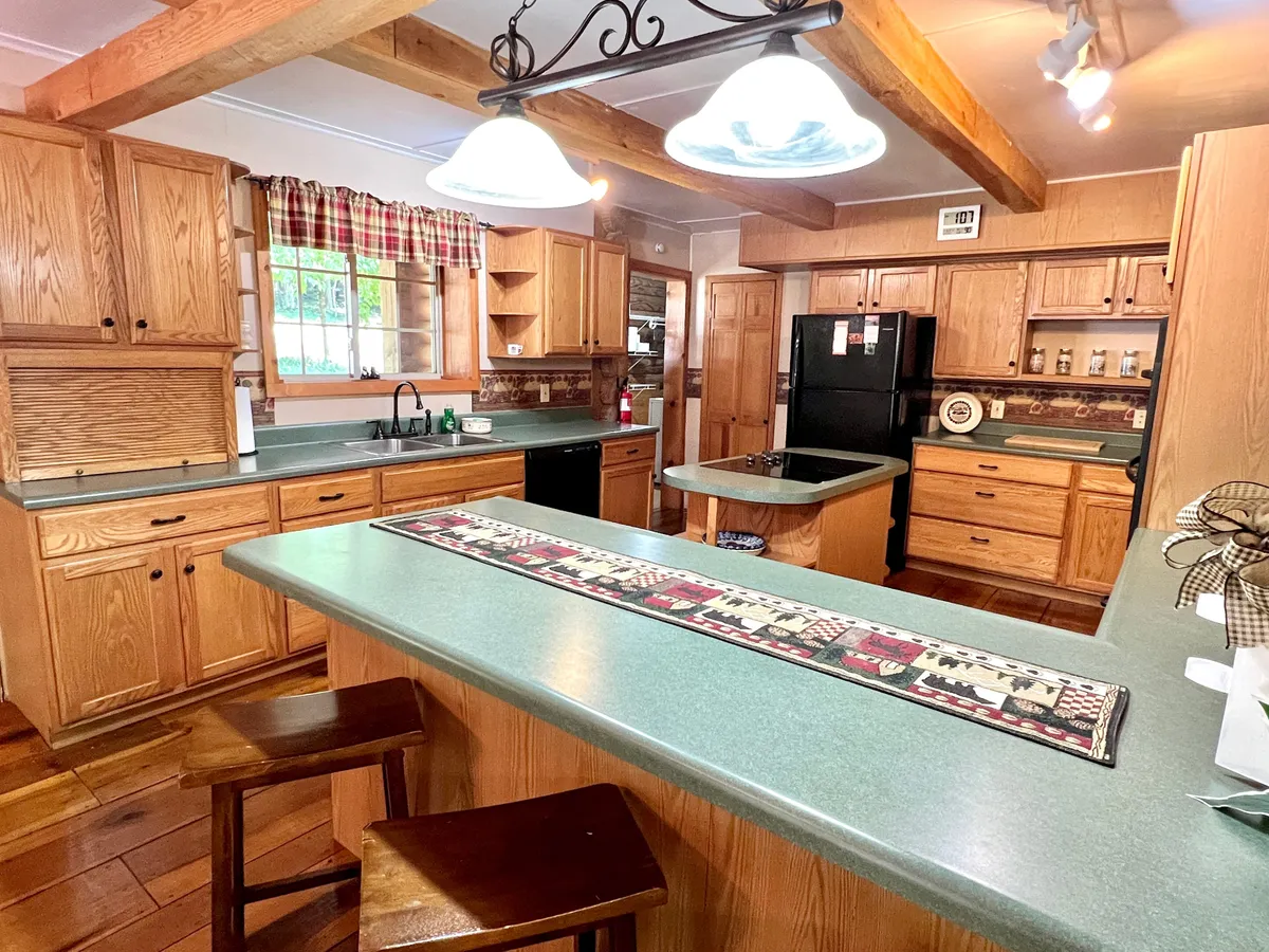 A spacious, well-lit kitchen with a large island, wooden cabinets, pendant lights, and natural light streaming in from a nearby window. This kitchen invites group cooking and easy meal prep, creating a welcoming atmosphere for making family recipes together.