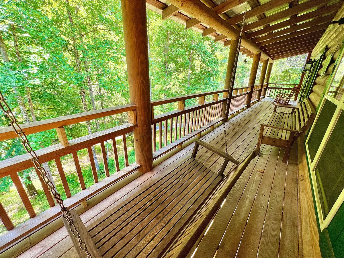 A cozy porch with wooden swings and a view of lush greenery, inviting guests to relax and enjoy peaceful moments outdoors. The setting suggests both solitude and the ability to connect with loved ones in a tranquil environment.